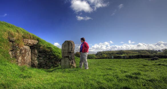 Photo of a tourist man at Bryn Celli Ddu burial chamber overlying a henge monument Isle of Anglesey North Wales.