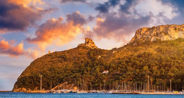 Beach of Cagliari (Poetto Sella del Diavolo) with Torre del Poetto tower and boats at sunset, Sardinia, Italy.