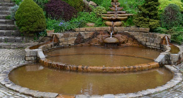 Photo of beautiful waterfall and Vesica Pool in the Chalice Well Garden, Glastonbury, England.