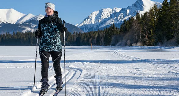 Photo of young woman cross country skiing on a snowy meadow with a view of the High Tatras-Kriváň.