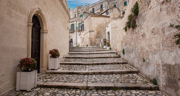 Photo of buildings in the old town of Matera, Basilicata, Southern Italy with blue sky and white clouds.