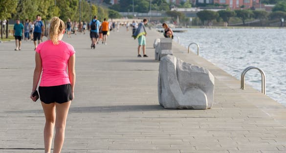 The Woman wearing pink sports top and shorts, walking on the waterfront promenade in Koper, Slovenia