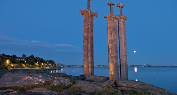 Photo of three large swords Sverd i Fjell at night stand on the hill as a memory to the Battle of Hafrsfjord in year 872 in Stavanger, Norway.