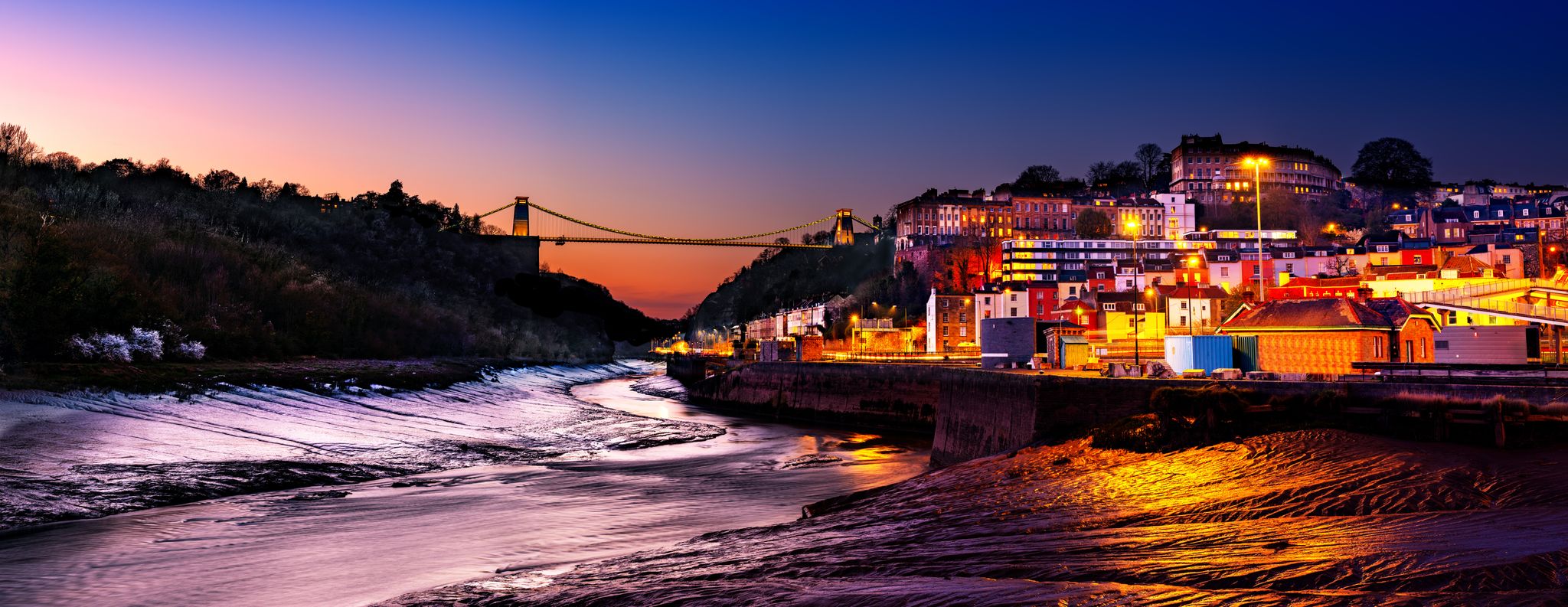 Panoramic photo of Clifton Suspension Bridge over the river Avon and Clifton Village, Bristol, England UK taken in the Blue Hour.