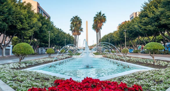 Photo of water fountain and flowers next to the palm trees in the Belen street of the Rambla de Almeria.