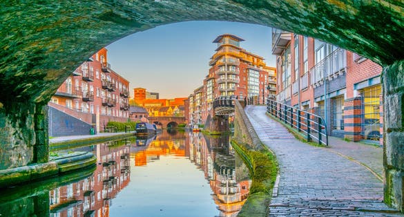 Photo of sunset view of brick buildings alongside a water channel in the central Birmingham, England.