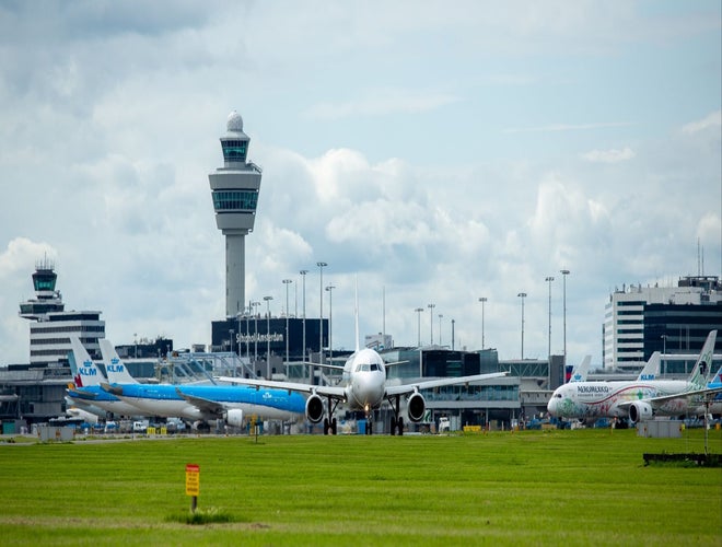Airplanes on the runway at Amsterdam Schiphol Airport with control towers in the background..jpg