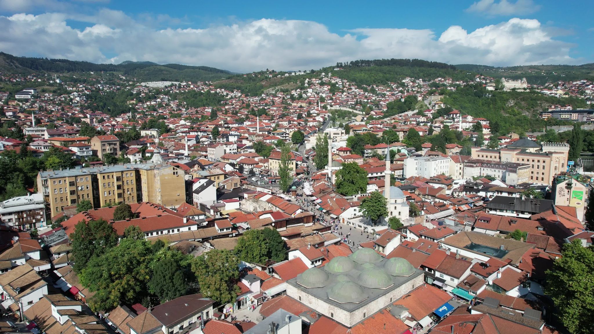Aerial drone view of the historical 6-domed building in brusa bezistan in Sarajove square, the busy street of the marketplace and the town square and the view of the bascarsi mosque in Bosnia