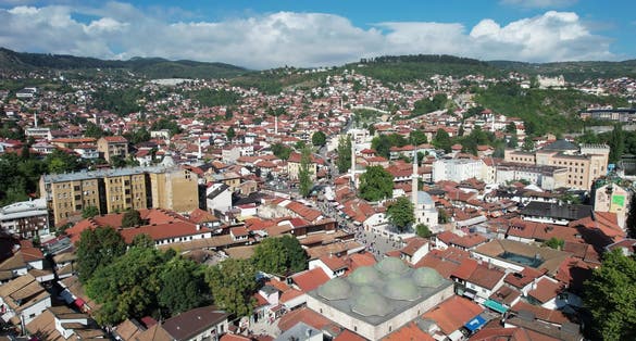 Aerial drone view of the historical 6-domed building in brusa bezistan in Sarajove square, the busy street of the marketplace and the town square and the view of the bascarsi mosque in Bosnia