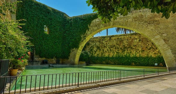 photo of big arch embracing crystal clear lake in Hort del Rei gardens, Palma de Mallorca in Spain.