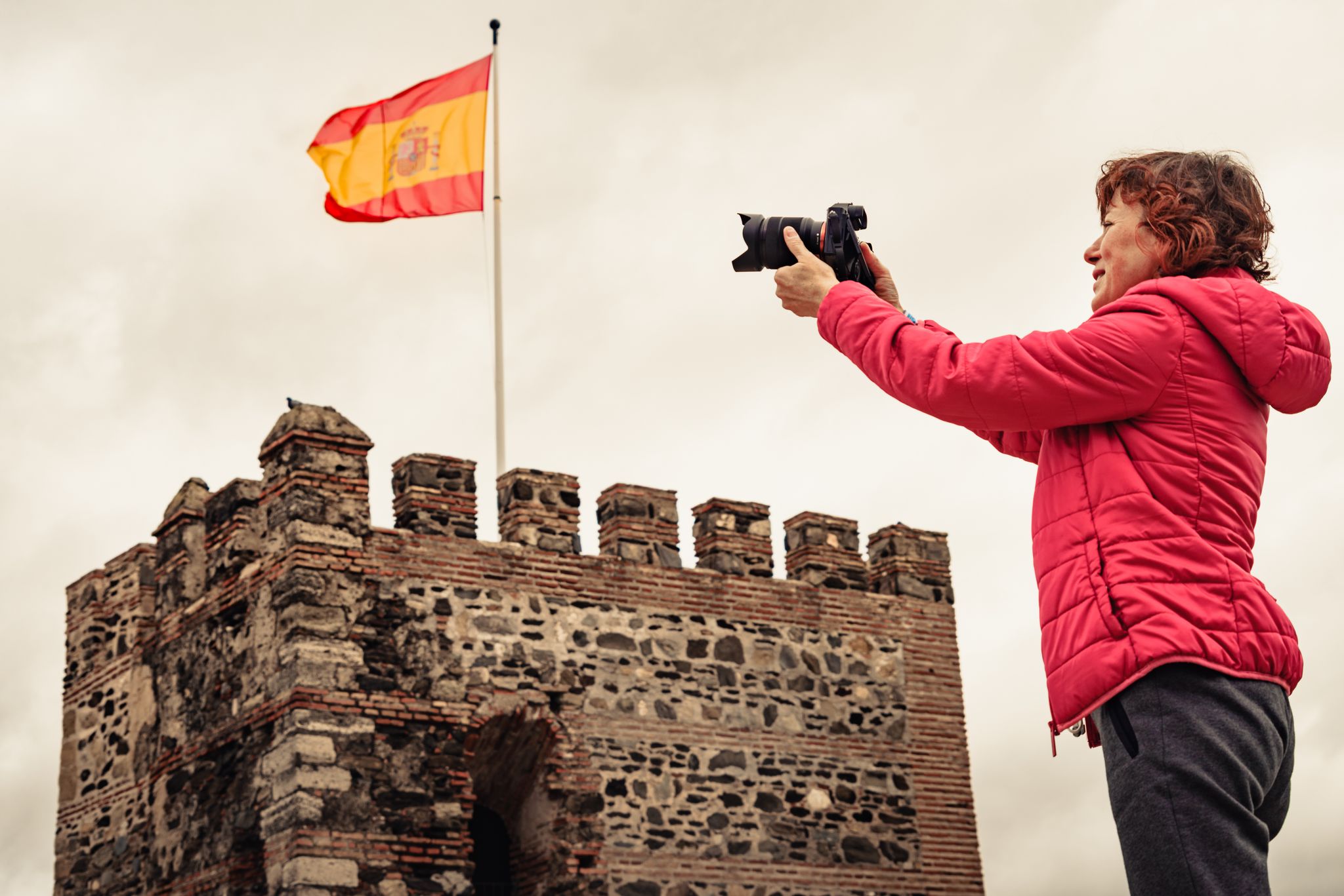 photo of tourist woman with camera taking travel picture on Sohail Castle in Fuengirola, Malaga Spain.