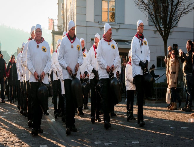 Men in white uniforms ringing cowbells during the Lucerne Festival Parade in December..jpg