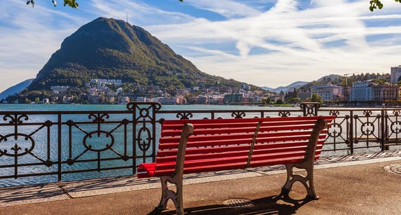 Photo of panoramic scenic view of the lake Lugano, mountains and city Lugano, Ticino canton, Switzerland. Scenic beautiful Swiss town with luxury villas.