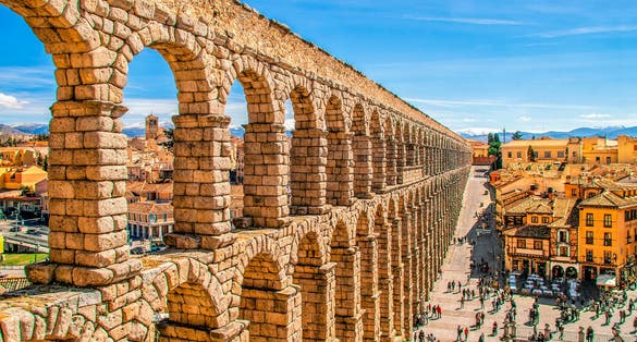 Photo of Ancient Roman aqueduct on Plaza del Azoguejo square and old building towns in Segovia, Spain.
