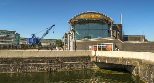 The Techniquest building in Cardiff Bay against a deep blue sky. In the foreground is one of the restored docks.