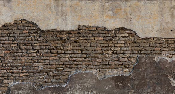 Dirty eroded cracked plaster fence panoramic scene. Destroyed crumbling cement mortar texture farm. Chipped structure stone facade.