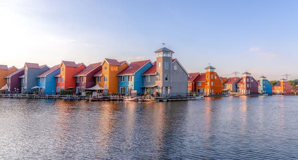 Colorful houses reflected in the frozen lake of Reitdiephaven in Groningen, Netherlands