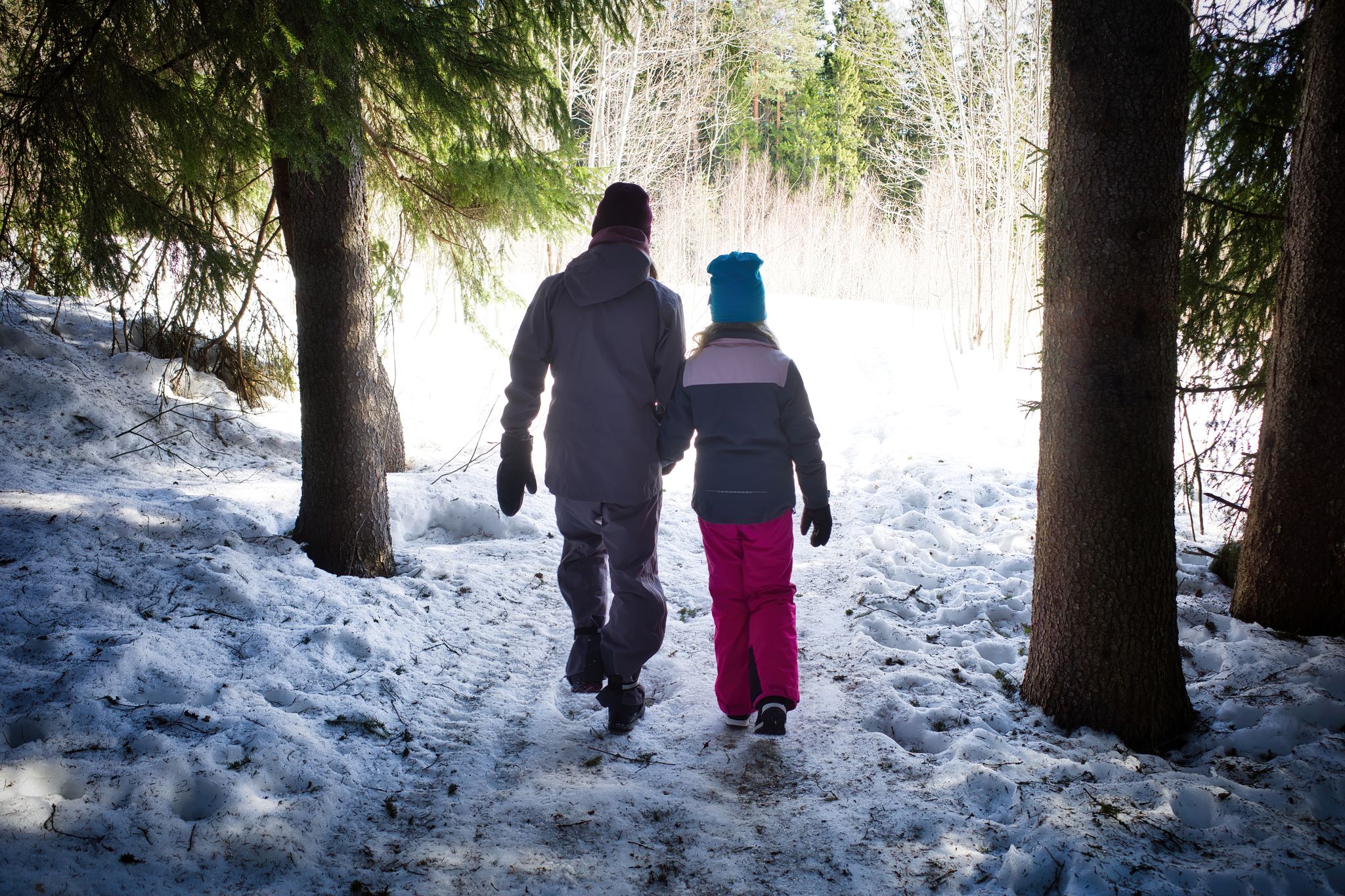 photo of view of Woman and child walking in winter forest towards the sun light. The winter walk in Skellefteå Sweden.