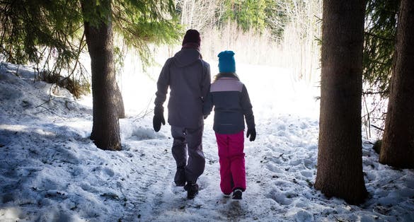 photo of view of Woman and child walking in winter forest towards the sun light. The winter walk in Skellefteå Sweden.