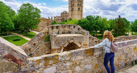 Photo of Woman overlooking the wall contemplating the beauty of the cathedral of Zamora Spain.