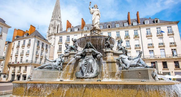 Photo of view on the Royal square with fountain and church tower in Nantes city in France.