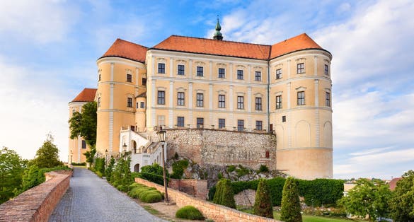 Photo of Mikulov castle or Mikulov Chateau on top of rock. View from garden of castle with beautiful staircase and bright blue sky with clouds in background, Mikulov, Moravia, Czech Republic.