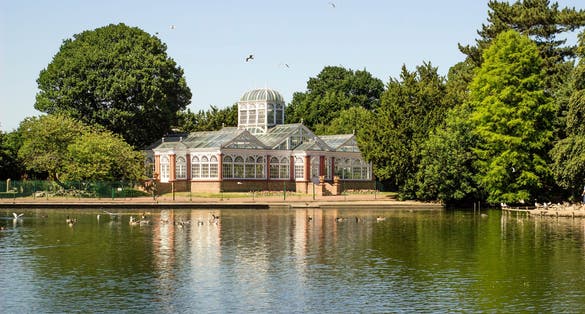 Photo of West Park in Wolverhampton, England. Beautiful view of lake, trees and Conservatory.