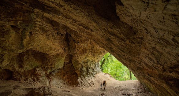photo of view of People visiting Istállós-kői Cave at summer - Mouth of a cave about 60 metres long and 17 metres high, Szilvásvárad, Hungary.
