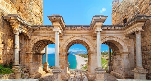 Photo of famous landmarks: Hadrian's Gate old town Kaleici district and Konyaalti beach in popular resort city Antalya, Turkey.