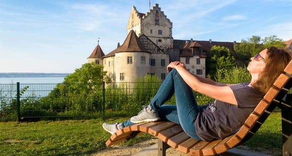 photo of adult girl tourist rests at Meersburg Castle overlooking Lake Constance at beautiful summer (Bodensee), Baden-Wurttemberg, Germany.