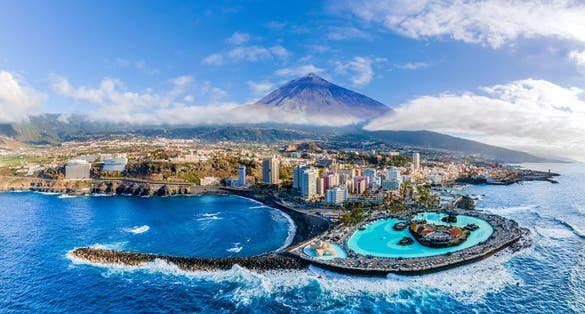 Photo of aerial view with Puerto de la Cruz, in background Teide volcano, Tenerife island, Spain.