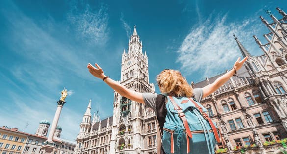 Photo of girl tourist traveler enjoys a Grand view of the Gothic building of the Old town Hall in Munich.