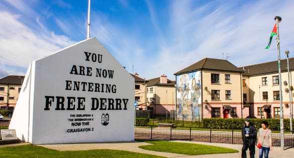The 'You are Now Entering Free Derry' Corner in Londonderry, Northern Ireland, with two passersby.