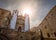 Photo of vView of the baroque church of San Francisco Javier de Caceres, Spain, in the Plaza de San Jorge at sunset with the sun backlit and pigeons in the sky .