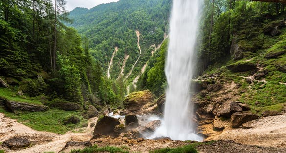 Peričnik Waterfall in Vrata Valley: Majestic beauty unveiled as sunlight illuminates cascading veil, shimmering rocks, and pristine surroundings. Nature's artistry awaits your discovery.