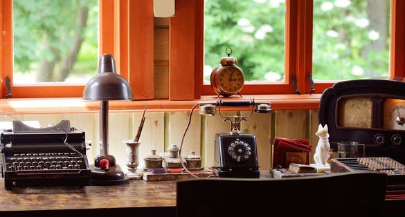 Interior of the cabinet of the old train station in Riga, Latvia. Wooden furniture, vintage clock, telephone and antique typewriter close-up. Concept image, past, history, museum, education