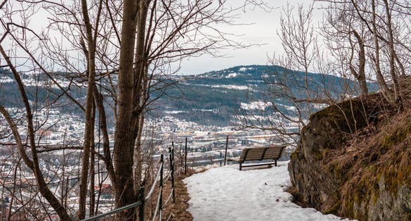 Photo of park bench on Drammen spiral with Drammen and mountains in the background.