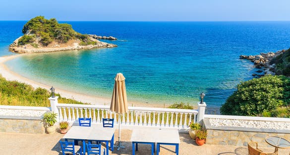Photo of tables with chairs on a terrace with view of beautiful Kokkari bay, Samos island, Greece.
