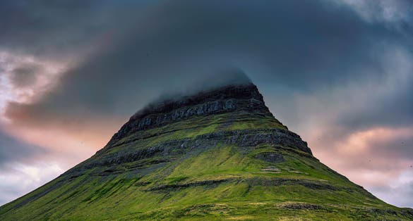 photo of Close up of Moody Kirkjufell mountain peak with cap cloud covered in the sunset on summer at Iceland
