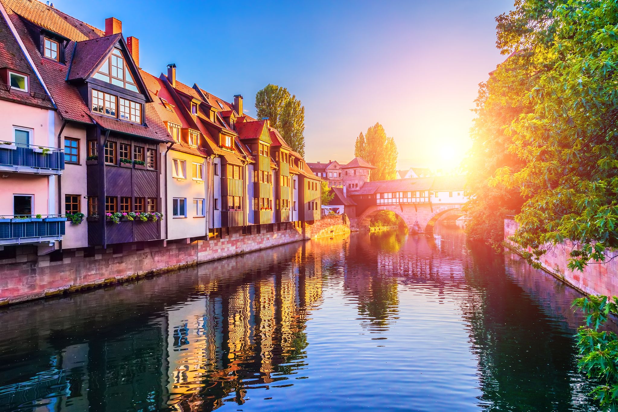 Photo of scenic summer view of the German traditional medieval half-timbered Old Town architecture and bridge over Pegnitz river in Nuremberg, Germany.