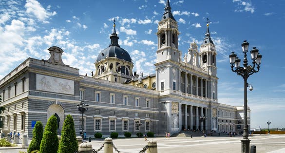 Photo of Side view of the Cathedral of Saint Mary the Royal of La Almudena on the blue sky background with white clouds in Madrid, Spain. Madrid is a popular tourist destination of Europe.