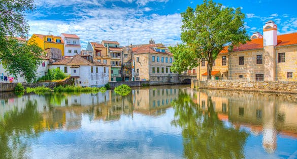 Photo of old buildings in Viseu reflected on a local creek, Portugal.