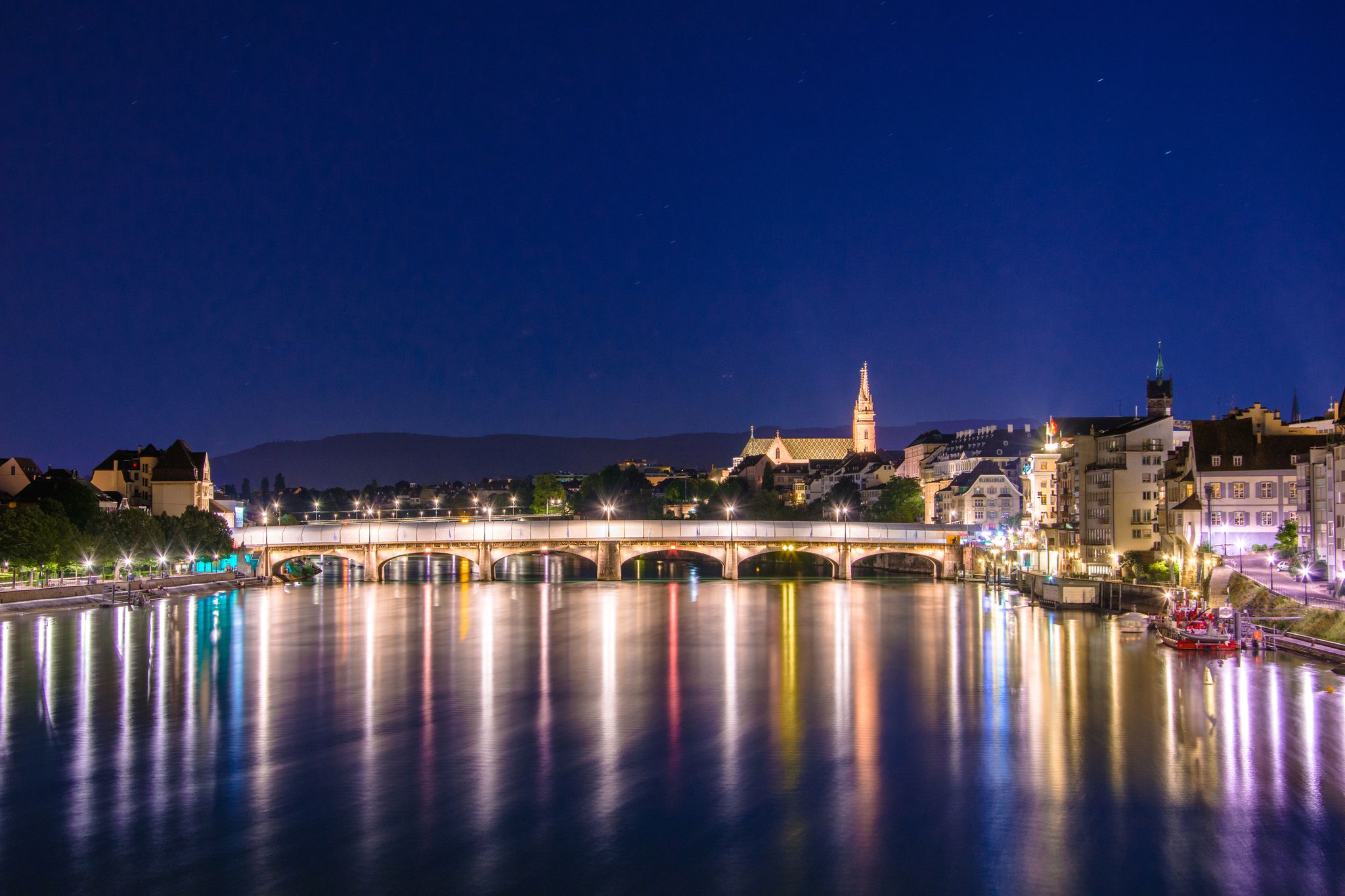 photo of night view of the Old Town of Basel with Middle bridge and red stone Munster cathedral and the Rhine River, Switzerland.