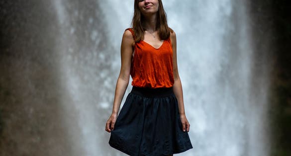 beautiful girl in a skirt stands in front of a powerful waterfall in slovenia, Peričnik falls