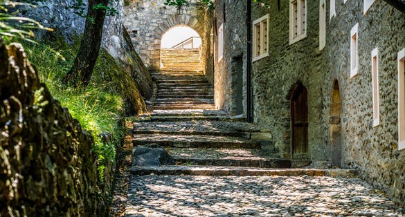 Photo of Pedestrian alley view of the Valere Basilica with old medieval buildings and paved road in Sion Valais Switzerland