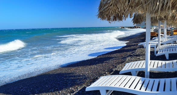 Photo of sunbeds at the beautiful Red beach. Santorini island, Greece.