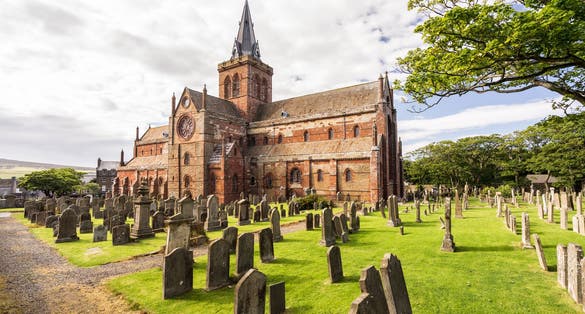 photo of St Magnus Cathedral and surrounding gothic graveyard in Kirkwall, Orkney Islands, Scotland. The holy red sandstone architecture is part of the church of Scotland.