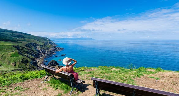 Photo of woman sitting on a bench in the Ribera near Estaca de Bares, La Coruña, Galicia, Spain.