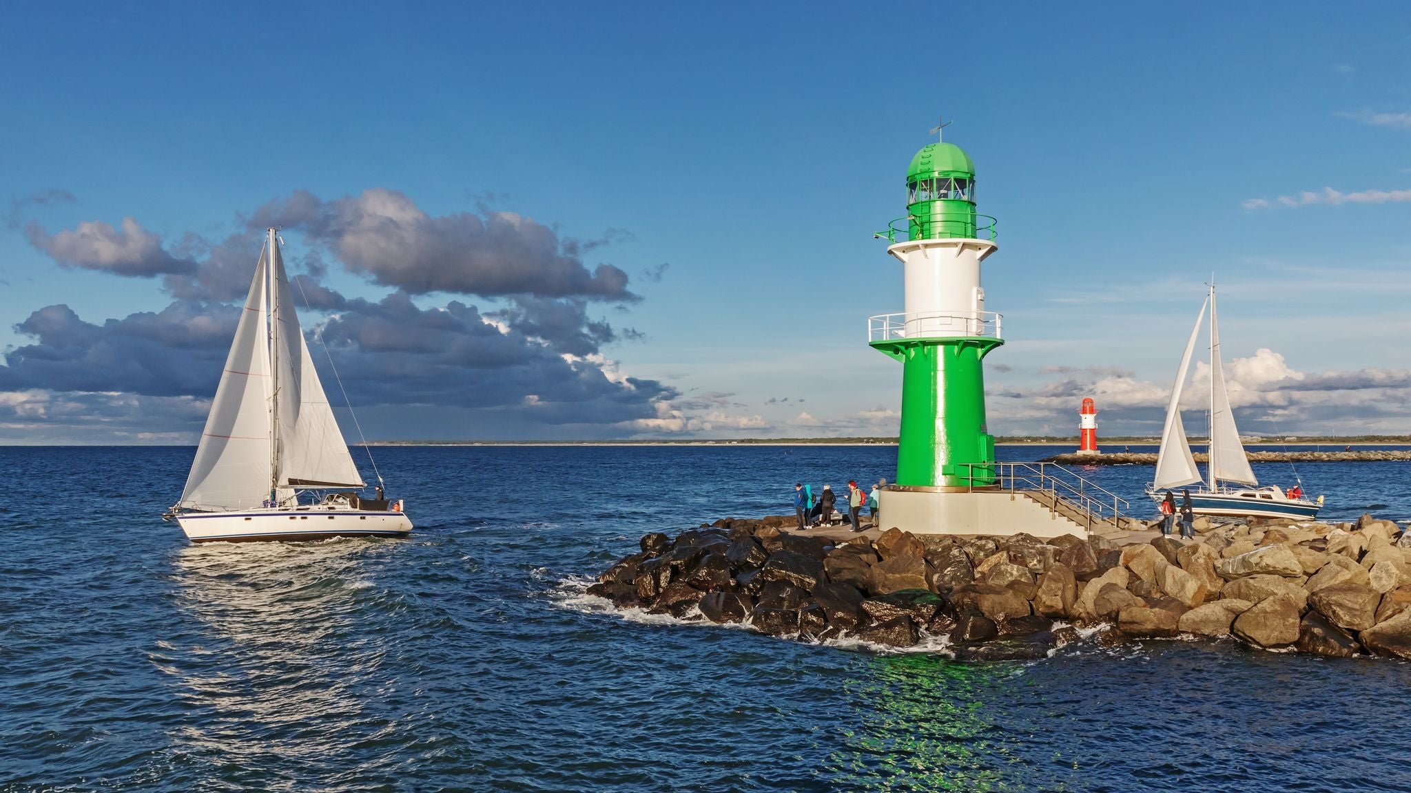 photo of Harbor entrance of Rostock-Warnemünde with a green and a red lighthouse (pier or mole light) with sail boats in Mecklenburg-Vorpommern, Germany.