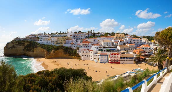 Photo of View of the sandy beach surrounded by typical white houses in a sunny spring day, Carvoeiro, Lagoa, Algarve, Portugal.